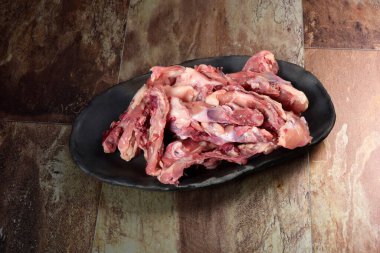 Siyah kil tabakta etli tavuk kemikleri, kahverengi taş arka plan. Tavuk çorbası seçimi