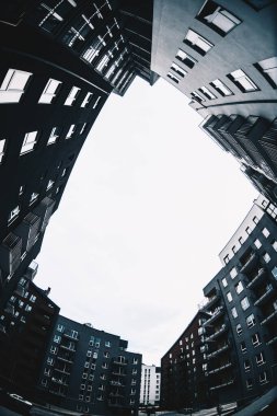 Yeni inşa edilmiş bir yerleşim bölgesinin geniş açılı şehir manzarası. Soğuk, karanlık tonlar. Modern binalar bir çember oluşturuyor