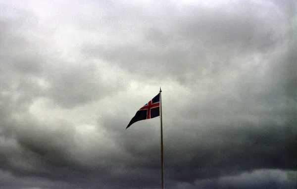 Fotografia Uma Bandeira Islândia Contra Nuvens Cinzentas Escuras Pesadas Paisagens — Fotografia de Stock