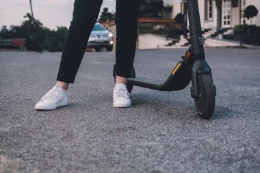 Modern aktif wooman onun elektrikli scooterının yanında duruyor.