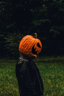 Siyah deri ceket ve balkabağı kostümü giyen bir adamın profil portresi.