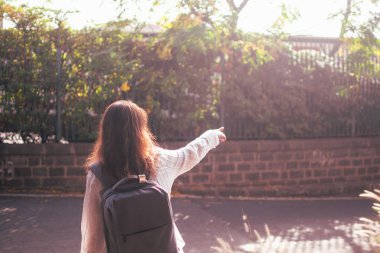 Gezgin kız uzaktaki bir şeyi işaret ediyor.
