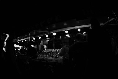 Palermo, İtalya - 4 Kasım 2023: Yerel bir pazardan balık ve diğer deniz ürünleri satın alan insanların siluetleri. Siyah ve beyaz