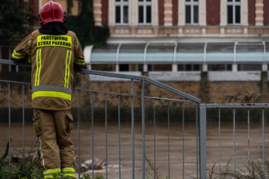 A Polish firefighter looking at Odra river in Opole and its water level caused by flood clipart