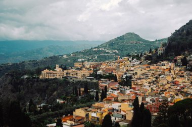 Sicilya, İtalya 'daki Taormina kasabasının evleri. Tepedeki renkli küçük evler dramatik bulutlu gökyüzüne karşı.