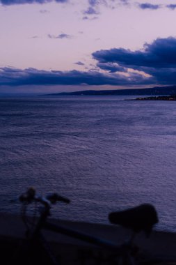 Taormina, İtalya 'da altın saat. Sakin bir akşam denizi ve arka planda bir kasaba. Önplanda bulanık bisiklet.
