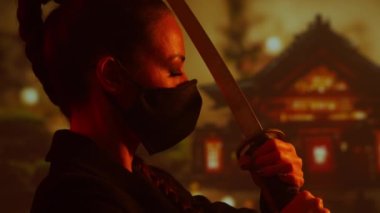 Maskeli ve katanalı genç ve güzel bir ninja kız. Geleneksel bir Japon tapınağının arka planındaki samuray kadın..