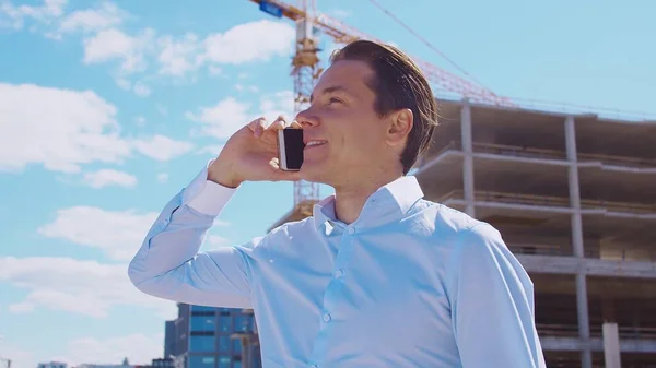 Business person standing in front of construction site. Office building and crane background. Development, real estate and investment concepts.