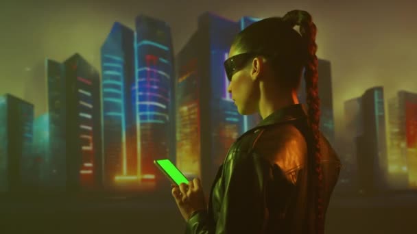 スマートフォンを搭載したサイバーパンク少女の肖像画 都市の高層ビルの背景に美しい若い女性 未来的概念 — ストック動画