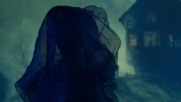 美しい魔女が夜の煙の背景に魔女を作る 丘の上の怖い家 ハロウィンのイメージ — ストック動画