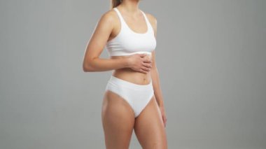 Genç, fit ve beyaz mayo giymiş güzel sarışın kadın gri arka planda poz veriyor. Sağlık, diyet, spor ve spor kavramı.