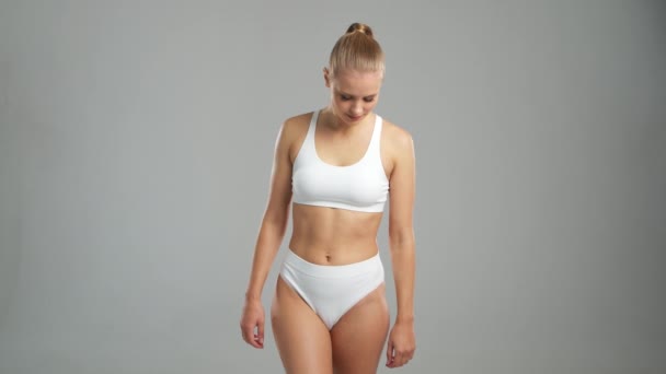 身穿白色泳衣的女人摆出灰色背景的姿势 体育和健身的概念 — 图库视频影像