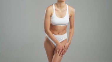 Genç, fit ve beyaz mayo giymiş güzel sarışın kadın gri arka planda poz veriyor. Sağlık, diyet, spor ve spor kavramı.