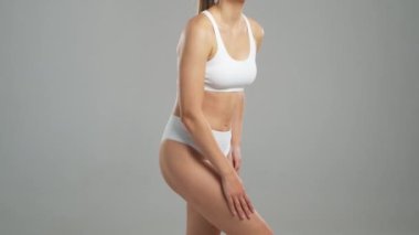 Genç, fit ve beyaz mayo giymiş güzel sarışın kadın gri arka planda poz veriyor. Sağlık, diyet, spor ve spor kavramı.