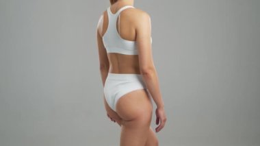 Genç, fit ve beyaz mayo giymiş güzel sarışın kadın gri arka planda poz veriyor. Sağlık, diyet, spor ve spor kavramı.