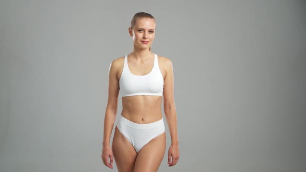Młoda Wysportowana Piękna Blondynka Białym Stroju Kąpielowym Pozująca Szarym Tle — Wideo stockowe