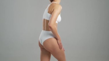 Genç, fit ve beyaz mayo giymiş güzel sarışın kadın gri arka planda poz veriyor. Sağlık, diyet, spor ve spor kavramı.