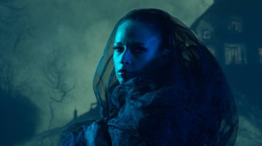 Güzel cadı gece dumanlı arka planda cadılık yapıyor. Tepedeki korkunç ev. Cadılar Bayramı resim kavramı.