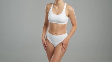 Genç, fit ve beyaz mayo giymiş güzel sarışın kadın gri arka planda poz veriyor. Sağlık, diyet, spor ve spor kavramı.