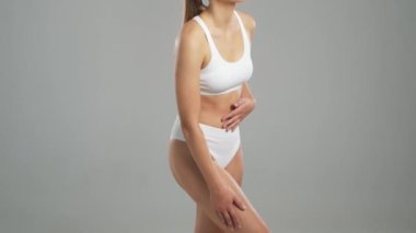 Genç, fit ve beyaz mayo giymiş güzel sarışın kadın gri arka planda poz veriyor. Sağlık, diyet, spor ve spor kavramı.