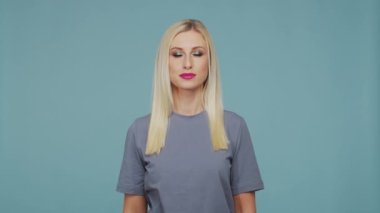 Stüdyodaki güzel sarışın kız. Mavi arka planda sevimli ve duygusal bir kızın portresi.