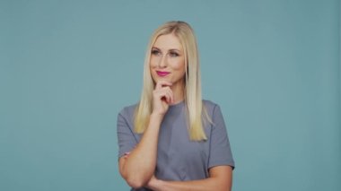 Stüdyodaki güzel sarışın kız. Mavi arka planda sevimli ve duygusal bir kızın portresi.