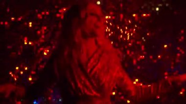 Parlak elbiseli, sarı saçlı, güzel, mutlu genç kız altın bir arka planda dans ediyor. Parti, disko ve tatil konsepti.