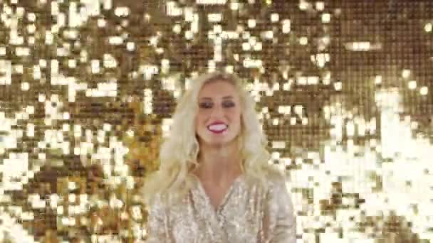 快乐的女孩 金发碧眼 穿着闪闪发光的衣服 在金色的背景上散落着五彩纸屑 迪斯科和假日的概念 — 图库视频影像