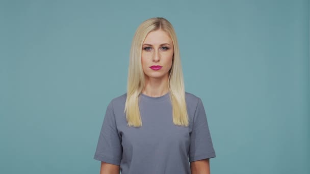 スタジオの若い美しいブロンドの女の子 青の背景にかわいいと感情的な女の子の肖像画 — ストック動画