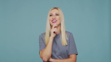 Stüdyodaki güzel sarışın kız. Mavi arka planda sevimli ve duygusal bir kızın portresi.