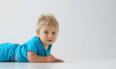 Stüdyoda küçük, mutlu ve gülümseyen bir bebek. Bir yaşındaki bir bebeğin portresi. Gri arka plan. Mutluluk kavramı.