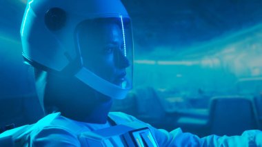 Yörünge istasyonunda uzay giysisi giymiş bir kadın astronot. Genç bir dişi kozmonot bir uzay gemisine pilotluk yapıyor. Galaktik seyahat ve bilim konsepti.