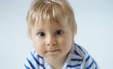 Stüdyoda küçük, mutlu ve gülümseyen bir bebek. Bir yaşındaki bir bebeğin portresi. Gri arka plan. Mutluluk kavramı.