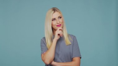 Stüdyodaki güzel sarışın kız. Mavi arka planda sevimli ve duygusal bir kızın portresi.