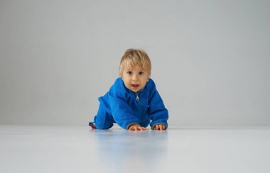 Stüdyoda küçük, mutlu ve gülümseyen bir bebek. Bir yaşındaki bir bebeğin portresi. Gri arka plan. Mutluluk kavramı.