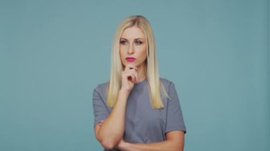 Stüdyodaki güzel sarışın kız. Mavi arka planda sevimli ve duygusal bir kızın portresi.