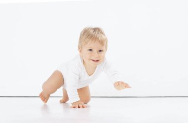 Stüdyoda küçük, mutlu ve gülümseyen bir bebek. Bir yaşındaki bir bebeğin portresi. İzole edilmiş beyaz arka plan. Mutluluk kavramı.