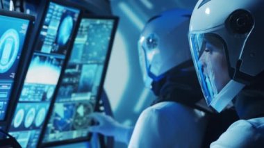 Yörünge istasyonunda uzay giysileri içinde bir astronot ekibi. Uzay gemisine pilotluk eden bir kozmonot mürettebatı. Uzayda kadın ve erkek. Galaktik seyahat ve bilim konsepti.