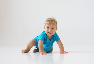 Stüdyoda küçük, mutlu ve gülümseyen bir bebek. Bir yaşındaki bir bebeğin portresi. Gri arka plan. Mutluluk kavramı.