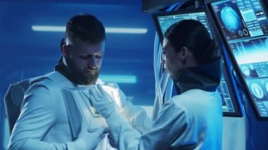 Yörünge istasyonunda uzay giysileri içinde bir astronot ekibi. Uzay giysisini hazırlayan bir kozmonot ekibi. Uzayda kadın ve erkek. Galaktik seyahat ve bilim konsepti.