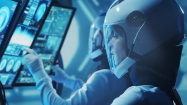Yörünge istasyonunda uzay giysileri içinde bir astronot ekibi. Uzay gemisine pilotluk eden bir kozmonot mürettebatı. Uzayda kadın ve erkek. Galaktik seyahat ve bilim konsepti.