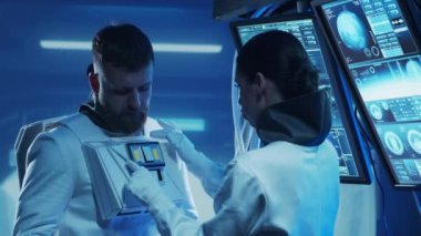 Yörünge istasyonunda uzay giysileri içinde bir astronot ekibi. Uzay giysisini hazırlayan bir kozmonot ekibi. Uzayda kadın ve erkek. Galaktik seyahat ve bilim konsepti.