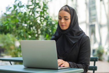 Close-up portrait of young and attractive muslim woman in hijab. Middle Eastern woman outdoor on the street. City background. The concept of business.