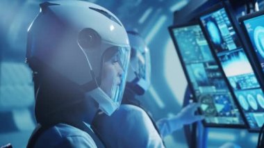 Yörünge istasyonunda uzay giysileri içinde bir astronot ekibi. Uzay gemisine pilotluk eden bir kozmonot mürettebatı. Uzayda kadın ve erkek. Galaktik seyahat ve bilim konsepti.