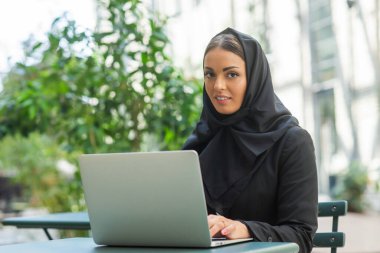 Close-up portrait of young and attractive muslim woman in hijab. Middle Eastern woman outdoor on the street. City background. The concept of business.