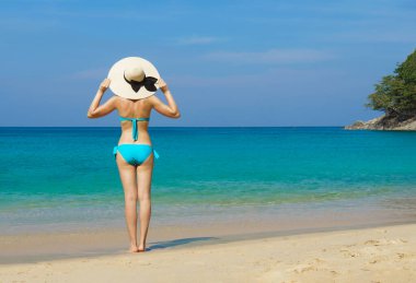 A beautiful woman in a swimsuit posing on a Thai beach at summer. Holiday, vacation, traveling and resort concept.