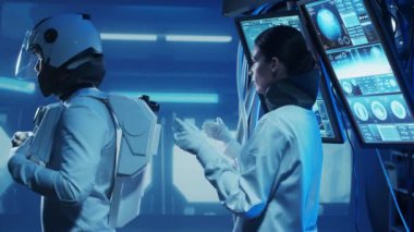 Yörünge istasyonunda uzay giysileri içinde bir astronot ekibi. Uzay giysisini hazırlayan bir kozmonot ekibi. Uzayda kadın ve erkek. Galaktik seyahat ve bilim konsepti.