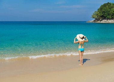 A beautiful woman in a swimsuit posing on a Thai beach at summer. Holiday, vacation, traveling and resort concept.