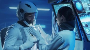Yörünge istasyonunda uzay giysileri içinde bir astronot ekibi. Uzay giysisini hazırlayan bir kozmonot ekibi. Uzayda kadın ve erkek. Galaktik seyahat ve bilim konsepti.
