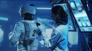 Yörünge istasyonunda uzay giysileri içinde bir astronot ekibi. Uzay giysisini hazırlayan bir kozmonot ekibi. Uzayda kadın ve erkek. Galaktik seyahat ve bilim konsepti.